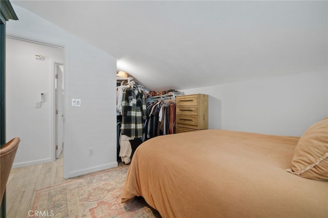 bedroom featuring lofted ceiling, a closet, and light hardwood / wood-style flooring