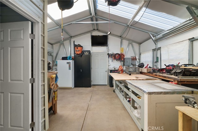 garage featuring a garage door opener, a workshop area, and white fridge