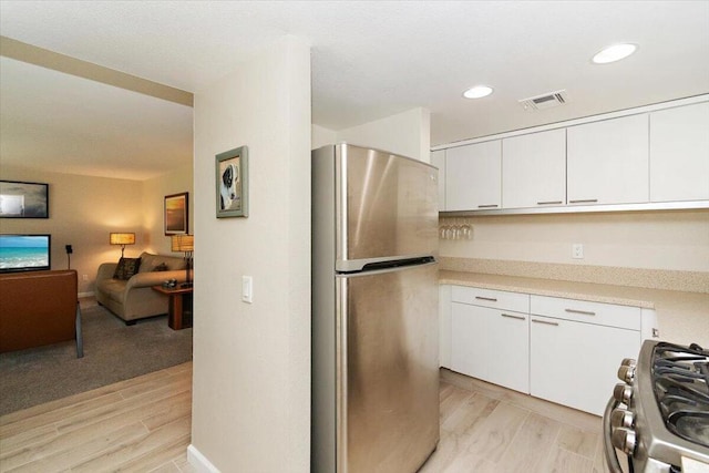 kitchen featuring light hardwood / wood-style flooring, white cabinets, and stainless steel appliances