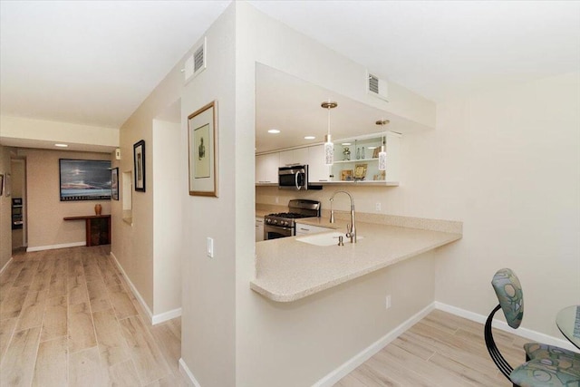 bar with appliances with stainless steel finishes, sink, decorative light fixtures, light hardwood / wood-style flooring, and white cabinetry