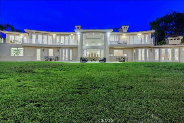 19 Marguerite Dr, Rancho Palos Verdes, CA 90275 - back of house at night with french doors, a lawn, a balcony, stucco siding, and a patio area