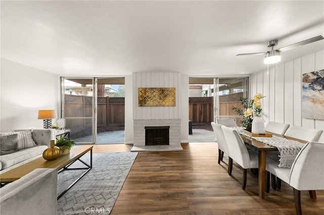 living room featuring hardwood / wood-style flooring, a brick fireplace, plenty of natural light, and ceiling fan