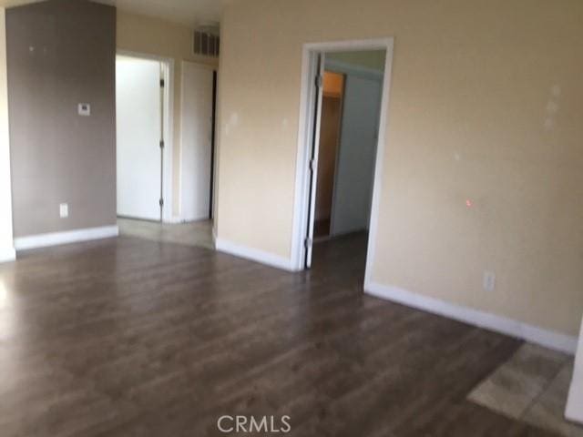 empty room with wood finished floors, baseboards, and visible vents