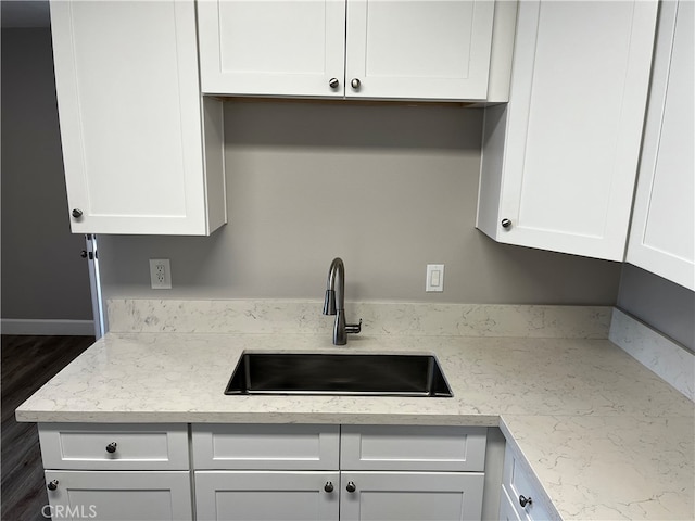 kitchen featuring light stone countertops, white cabinetry, dark hardwood / wood-style floors, and sink