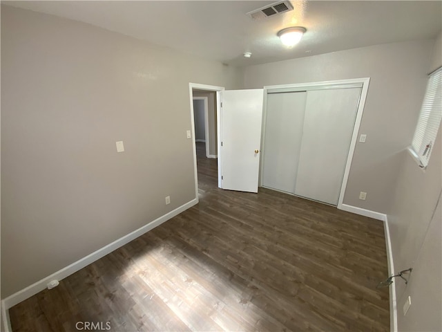 unfurnished bedroom featuring dark hardwood / wood-style floors and a closet