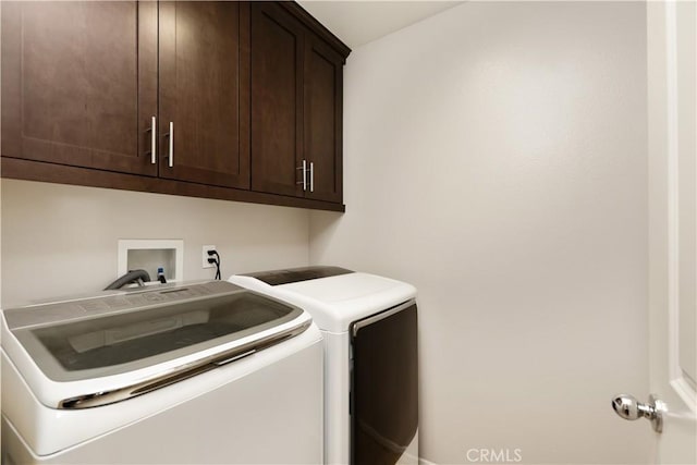 clothes washing area featuring cabinets and washer and clothes dryer