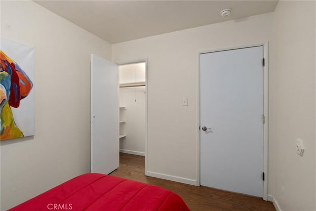 bedroom featuring a walk in closet, hardwood / wood-style flooring, and a closet