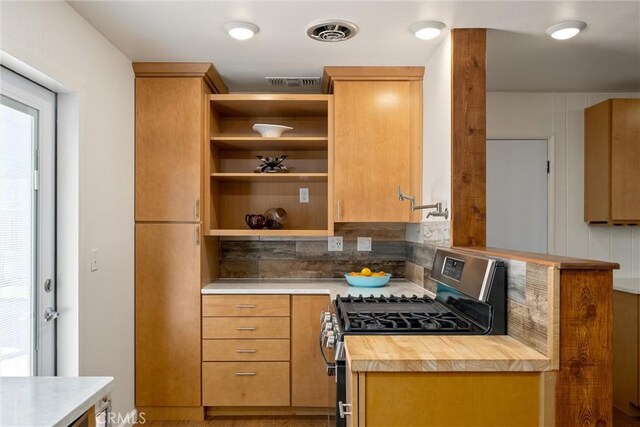 kitchen featuring gas stove, butcher block countertops, and backsplash