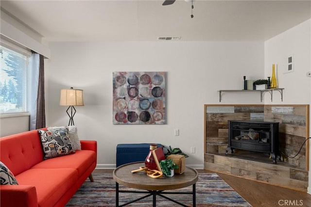 living room featuring ceiling fan, dark hardwood / wood-style flooring, and a wood stove