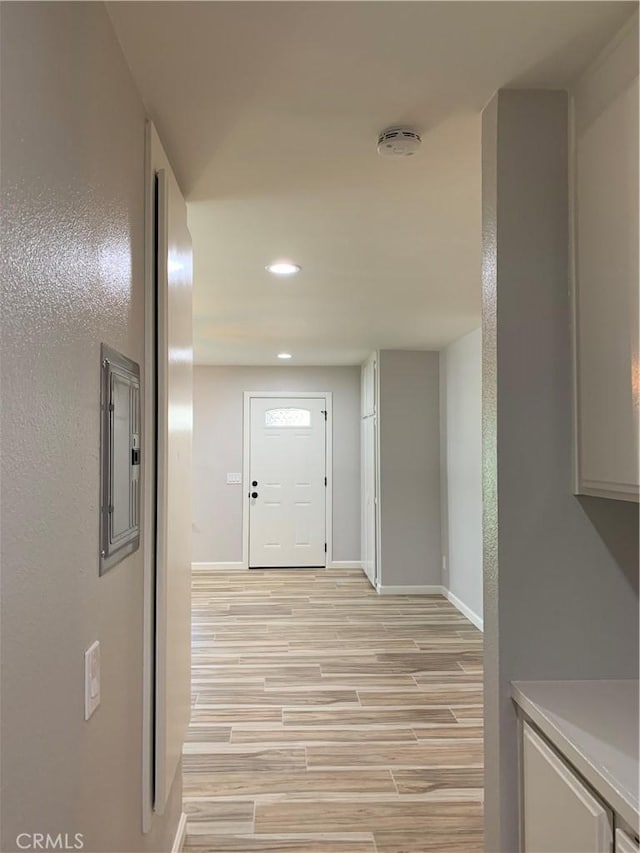 hallway featuring baseboards, recessed lighting, and light wood-style floors