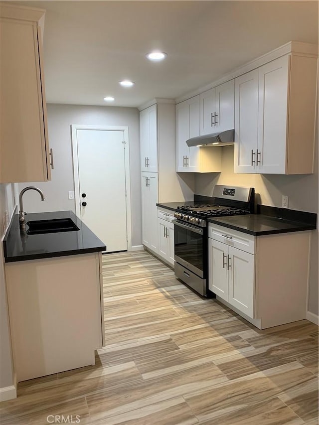 kitchen with stainless steel range with gas cooktop, white cabinetry, recessed lighting, under cabinet range hood, and a sink