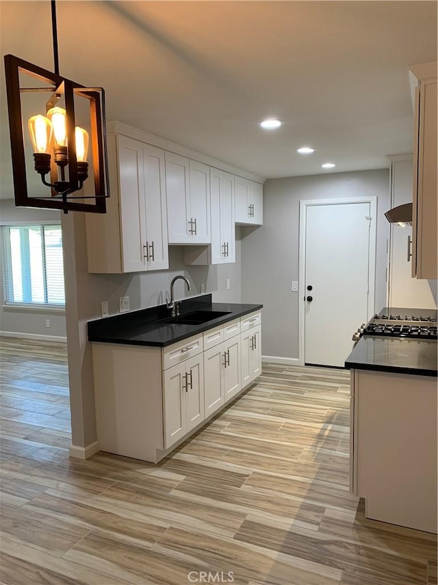 kitchen with recessed lighting, baseboards, a sink, and dark countertops