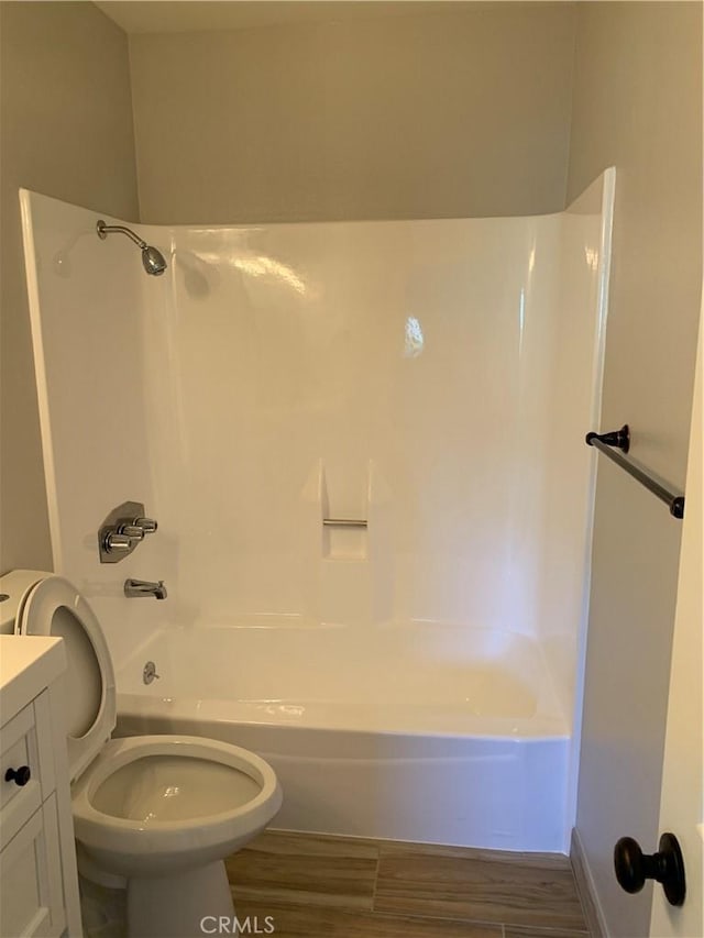 bathroom with toilet, wood finished floors, vanity, and bathing tub / shower combination
