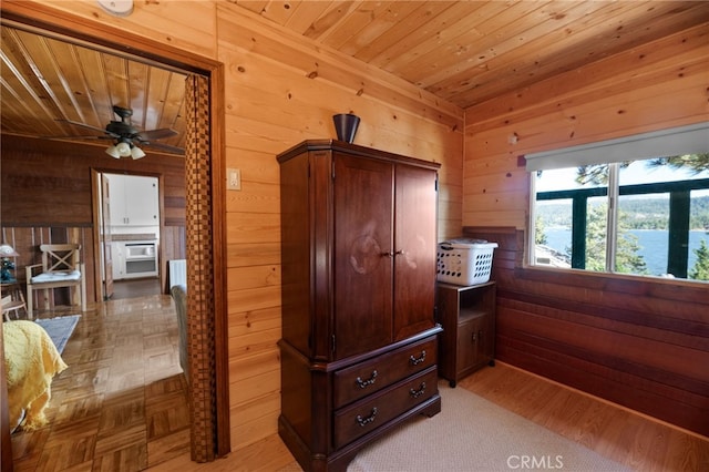 interior space featuring wood walls, ceiling fan, and wooden ceiling