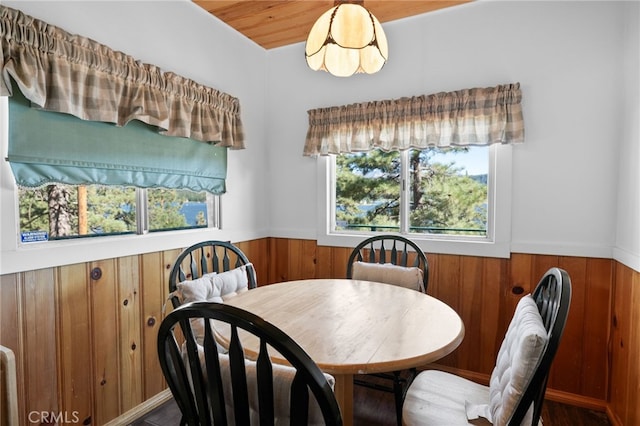 dining room featuring wooden ceiling and wooden walls