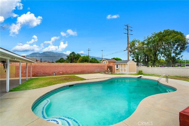 view of pool with a mountain view, a shed, and a patio