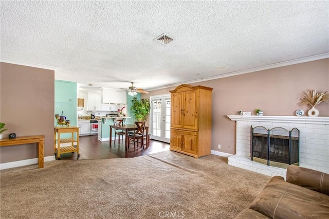 living room featuring ceiling fan, crown molding, carpet floors, and a fireplace