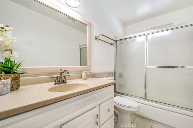 full bathroom featuring toilet, tile patterned flooring, vanity, and combined bath / shower with glass door