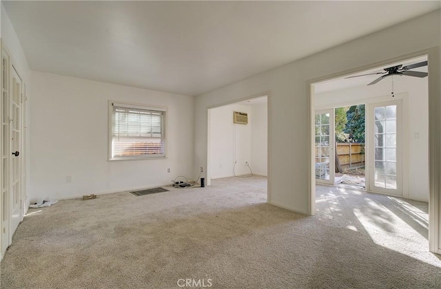 carpeted empty room featuring french doors, a wall unit AC, and ceiling fan