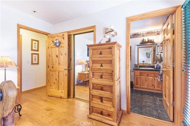 hallway with a sink, light wood-style flooring, and baseboards