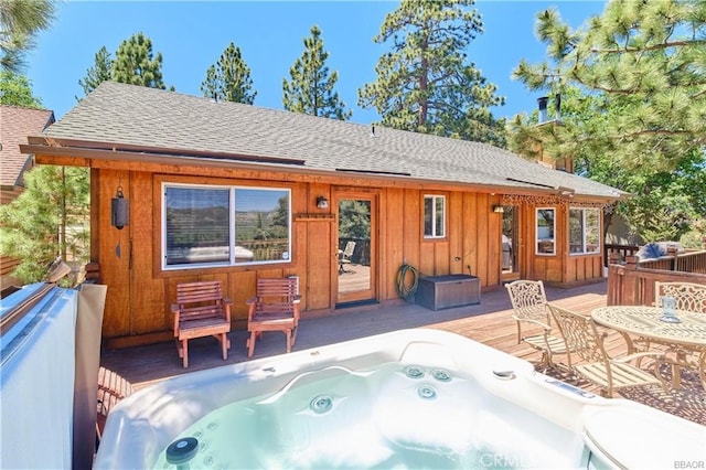 back of house with a deck, a shingled roof, board and batten siding, and hot tub deck surround