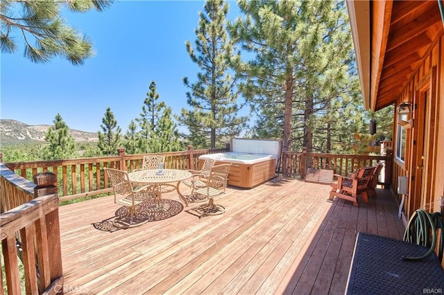 wooden deck with outdoor dining area, a mountain view, and a hot tub