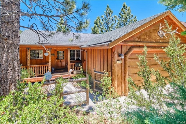 exterior space featuring roof with shingles, a porch, board and batten siding, and an attached garage