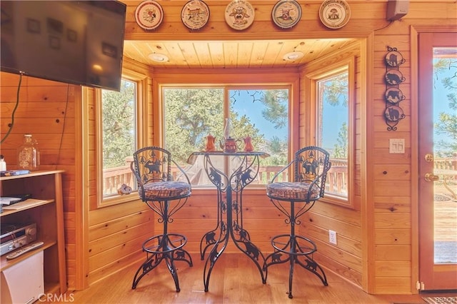 dining space with light wood-type flooring, wood walls, and wooden ceiling