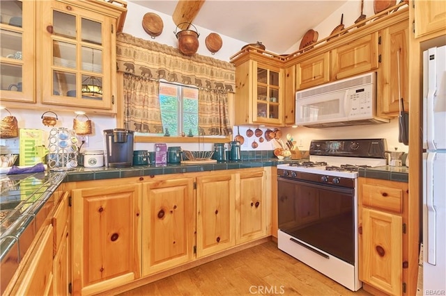 kitchen with glass insert cabinets, white appliances, light wood-style flooring, and tile countertops