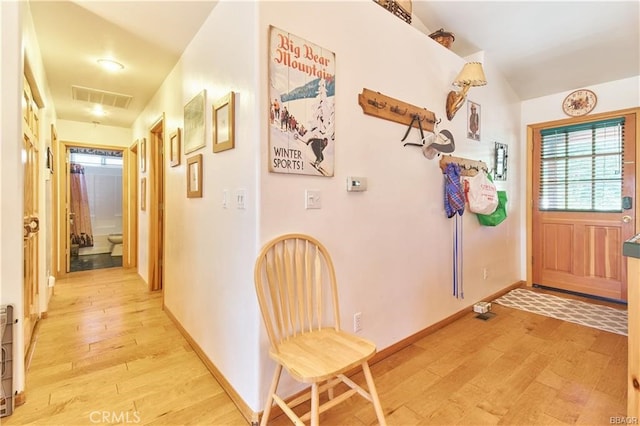 corridor featuring light wood-style flooring, visible vents, and baseboards