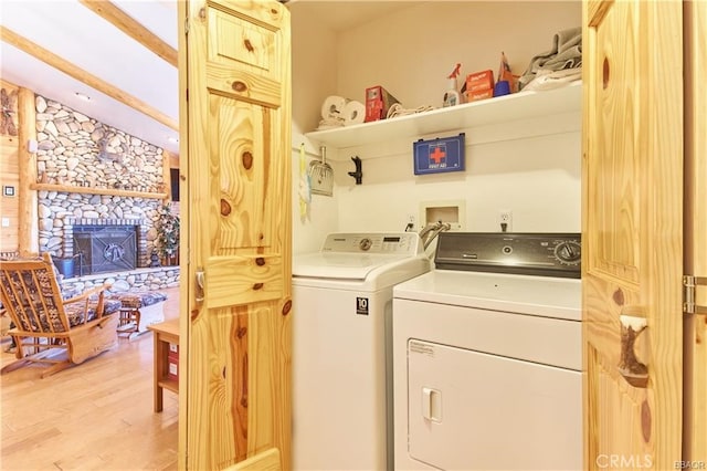 washroom with light wood-style floors, laundry area, a fireplace, and independent washer and dryer