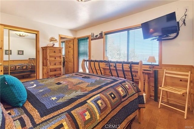 bedroom with a wainscoted wall and wood finished floors