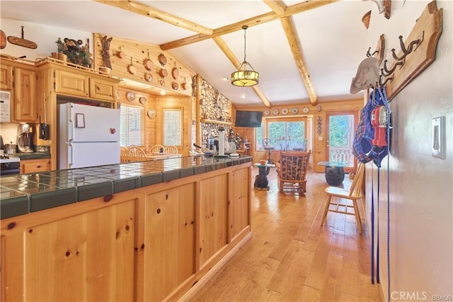 kitchen featuring lofted ceiling with beams, white appliances, tile counters, light wood finished floors, and pendant lighting