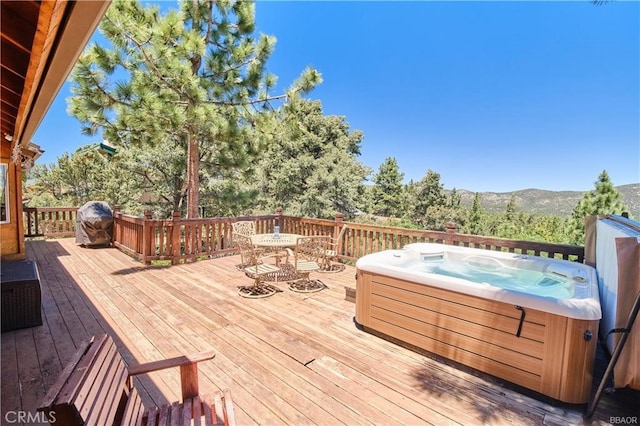 wooden deck with a hot tub and a mountain view