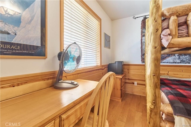 dining space featuring electric panel, a wainscoted wall, wood walls, and light wood-style flooring