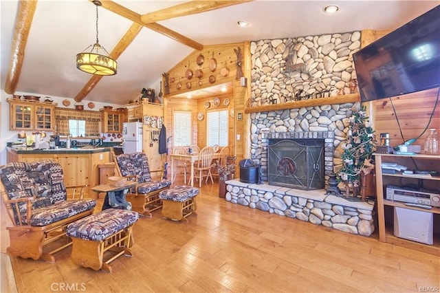 living room with light hardwood / wood-style floors, lofted ceiling with beams, and a fireplace