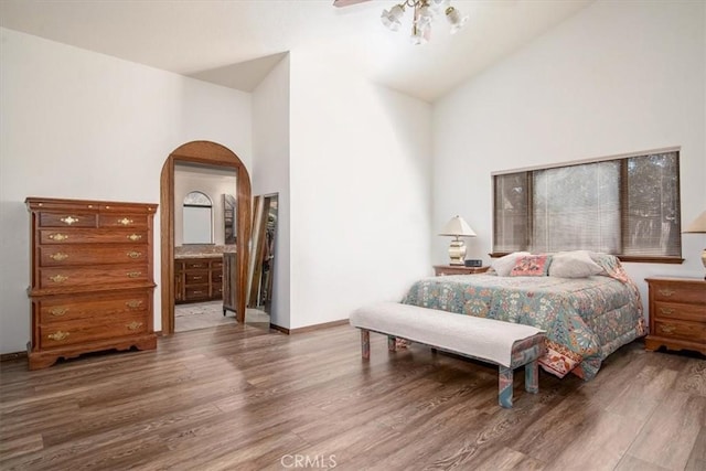 bedroom with high vaulted ceiling, hardwood / wood-style floors, and ensuite bath