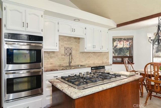 kitchen with stainless steel appliances, white cabinetry, sink, and light stone counters