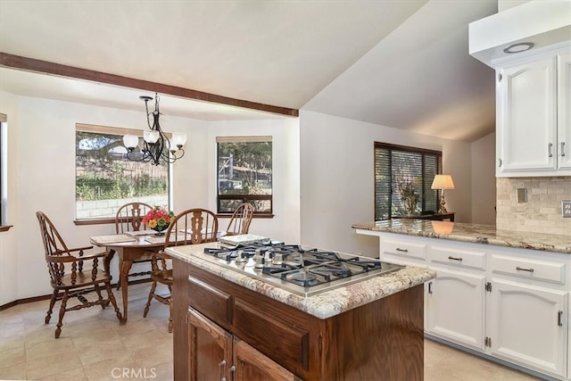 kitchen with a healthy amount of sunlight, white cabinets, decorative backsplash, decorative light fixtures, and stainless steel gas stovetop