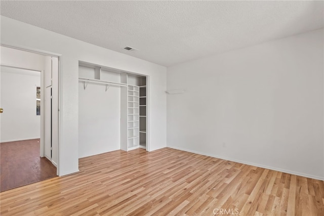 unfurnished bedroom with a textured ceiling, light hardwood / wood-style flooring, and a closet