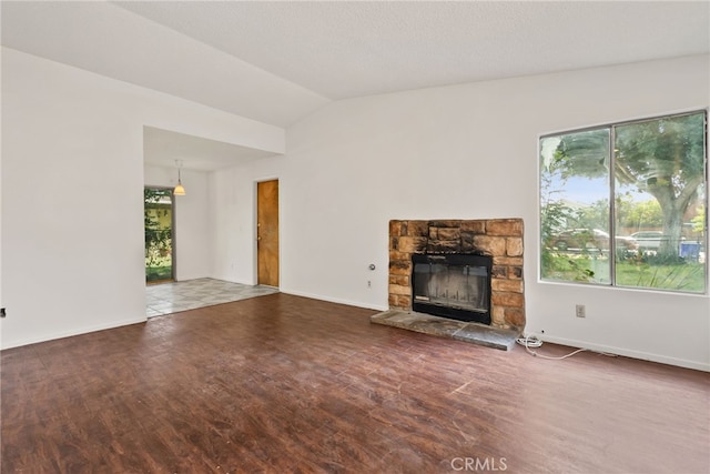 unfurnished living room featuring a stone fireplace, a textured ceiling, lofted ceiling, and dark hardwood / wood-style floors