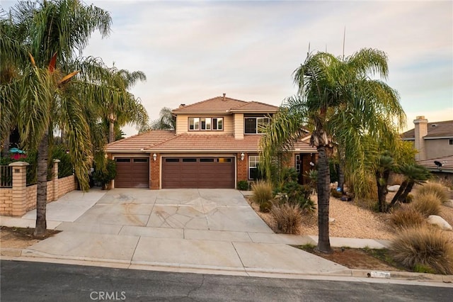 view of front of house featuring a tile roof, concrete driveway, brick siding, and a garage