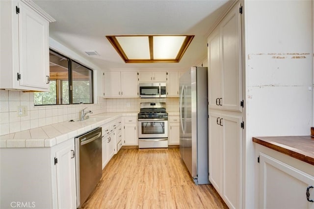 kitchen with appliances with stainless steel finishes, white cabinetry, sink, and tasteful backsplash