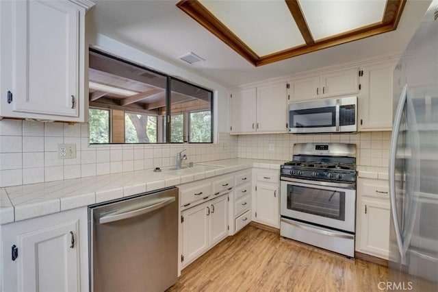 kitchen featuring tile counters, white cabinetry, sink, and stainless steel appliances