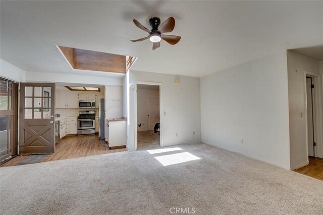 unfurnished living room with light hardwood / wood-style floors, ceiling fan, and a skylight