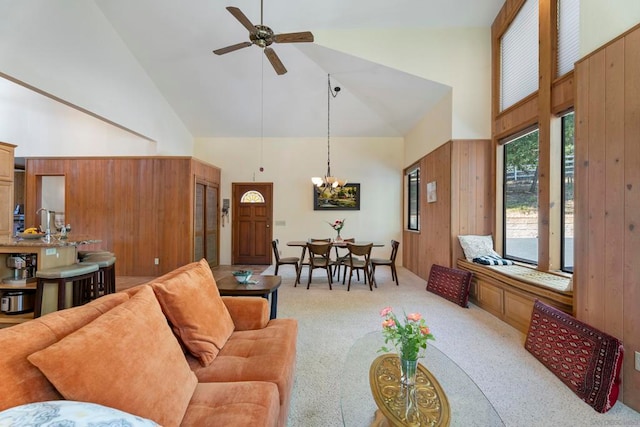 living room with ceiling fan with notable chandelier, wooden walls, and high vaulted ceiling