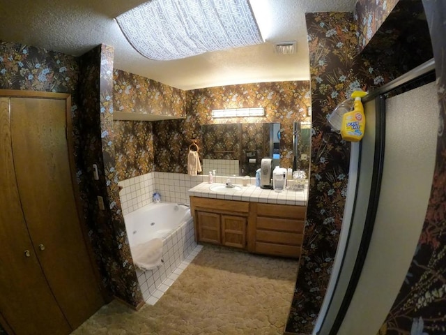 bathroom featuring a textured ceiling, vanity, and plus walk in shower