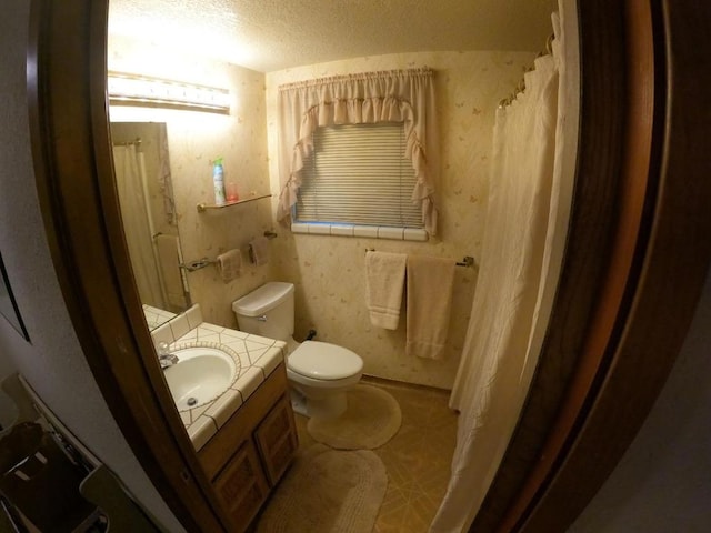 bathroom with vanity, toilet, a textured ceiling, and a shower with shower curtain