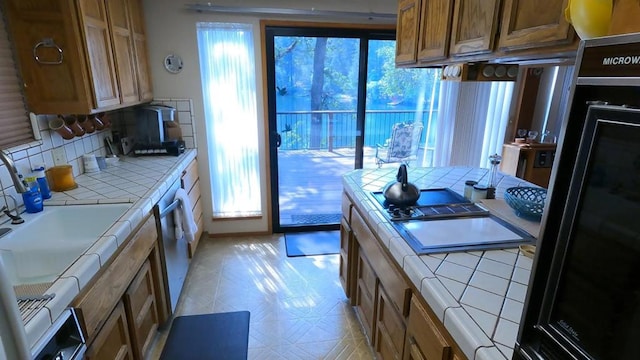 kitchen with tile counters, dishwasher, and tasteful backsplash