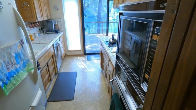 kitchen with decorative backsplash, stainless steel appliances, and tile counters